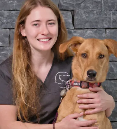 A portrait photo of Justine with a brown dog looking directly at the camera